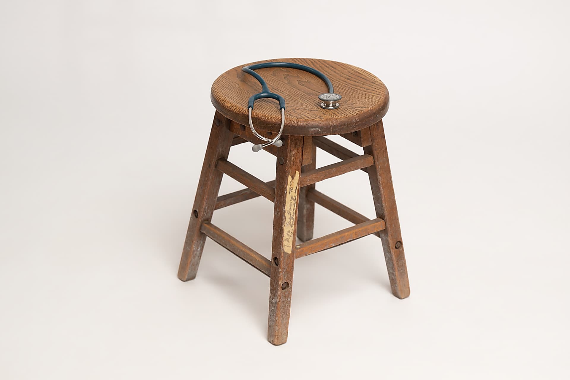 My aunt's wooden nursing stool with a stethoscope, a symbol of unhurried, human-centered care